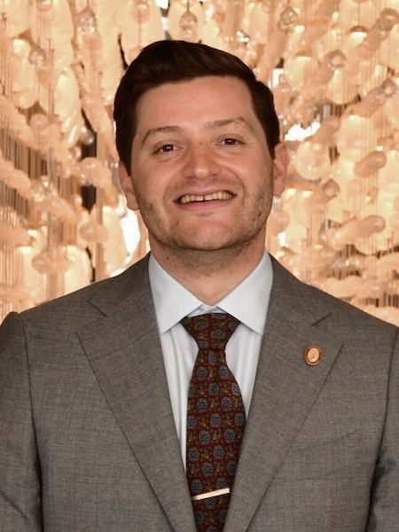 Man in suit smiles at camer with brightly lit background